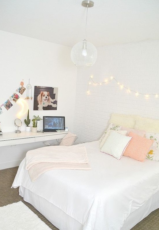 a neutral teen bedroom with a floating desk and vanity, a bed with pastel pillows and lights on the wall