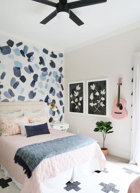 a pretty teen bedroom with a brushstroke accent wall, pink and blue textiles and a pink guitar on the wall