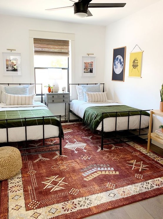 a stylish boho shared teen bedroom with metal beds, gallery walls, a printed rug and a wicker ottoman