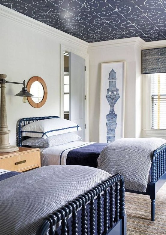 a stylish navy and white traditional shared teen bedroom with blue beds, wooden furniture and a printed ceiling