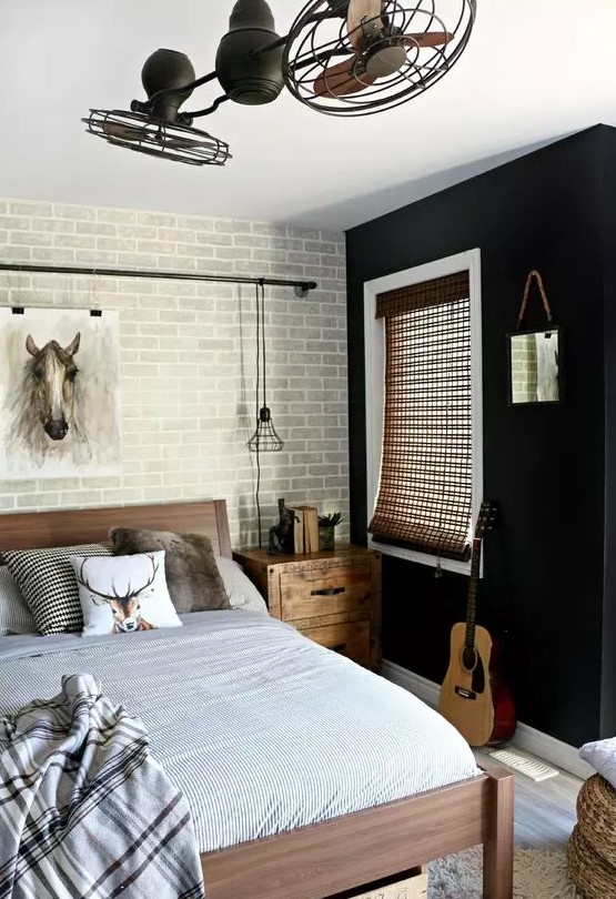 a stylish teen bedroom with a black accent wall and a brick one, a wooden bed and nightstands, neutral textiles, fans and a pendant lamp of metal