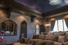 a bold and pretty home theater with a Harry Potter ceiling, taupe seating furniture, a leather ottoman and vintage floor lamps