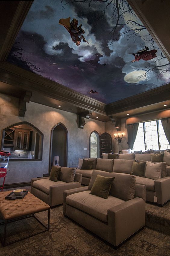 a bold and pretty home theater with a Harry Potter ceiling, taupe seating furniture, a leather ottoman and vintage floor lamps