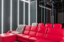 a bold modern home theater with grey walls with built-in lights, hot red seating furniture, a glazed wall and a black ceiling