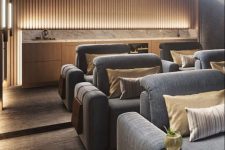 a chic contemporary home theater with a light-stained bar, built-in lights and grey seating furniture and neutral pillows