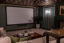 a refined home theater with grey and gold walls, a beautiful ceiling, neutral seating furniture, a stained console table and a large screen