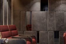 a refined moody home theater with upholstered panels on the walls, red and brown chairs, built-in lights and elegant side tables