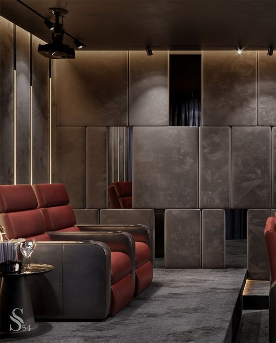 a refined moody home theater with upholstered panels on the walls, red and brown chairs, built in lights and elegant side tables