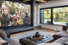 a welcoming home theater with a large window, a grey sofa, a leather ottoman, a large screen and a paneled ceiling is cool