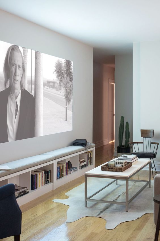 an airy home theater done in neutrals, with two storage benches, elegant furniture and a rug is a cool space with a Scandinavian feel