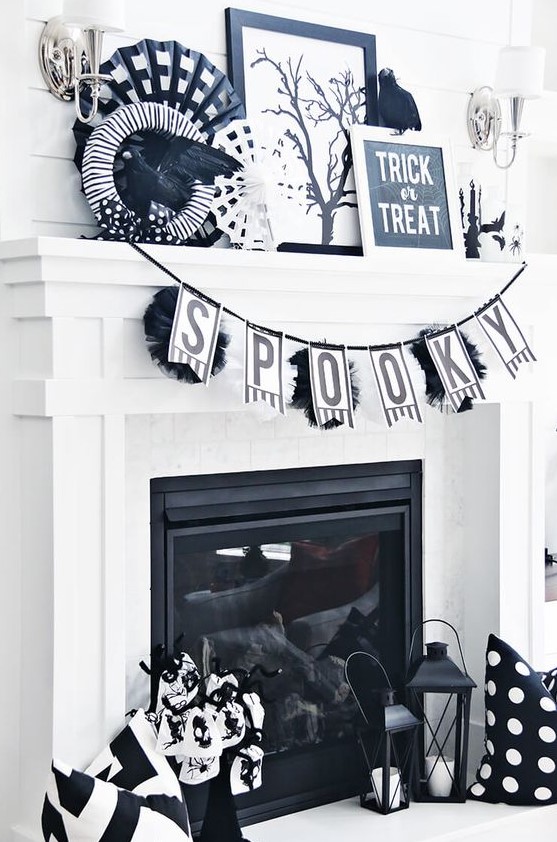 a black and white Halloween mantel with a garland, a wreath, a sign, some paper fans, a blackbird and some spiders