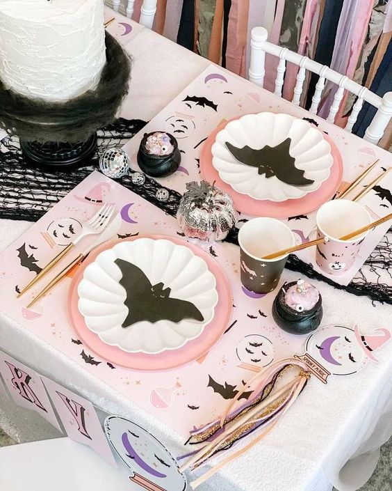 a black, blush and white Halloween tablescape with bat prints all over is a cool idea for a kids' party
