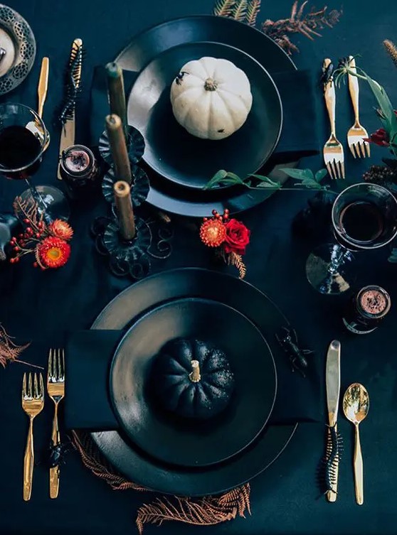 a bold modern Halloween tablescape with red blooms, spiders and snakes, gold cutlery, white and black pumpkins