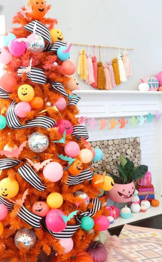 a colorful Halloween tree in orange, with pastel ornaments and balloons, striped garlands and jack-o-lanterns