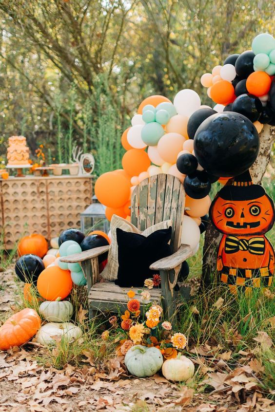a colorful vintage-inspired Halloween space with pastel and bright balloons, a bold cat prop and some blooms and pumpkins
