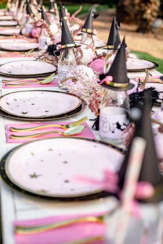 a cute witch table setting with pink napkins, star plates, witches' hats and neutral pumpkins is amazing