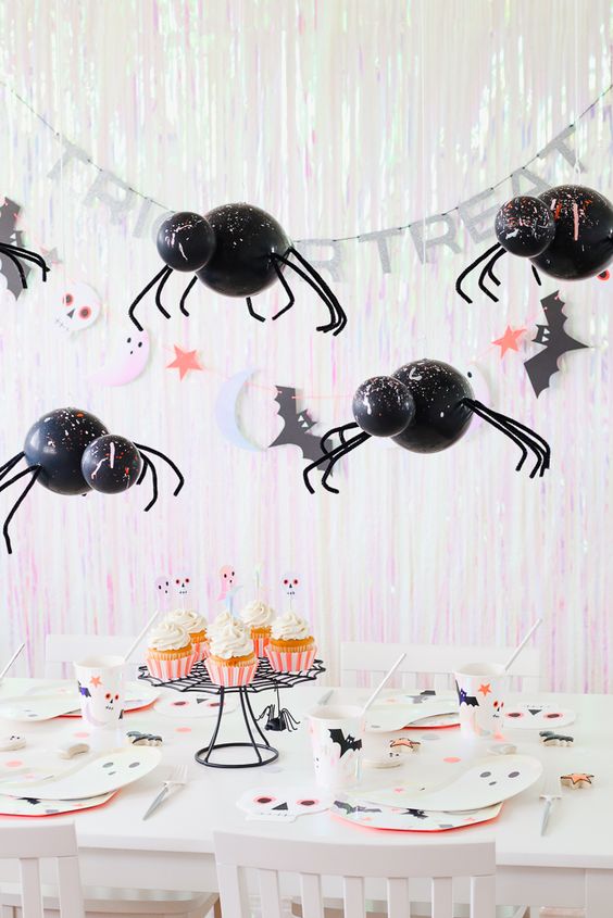 a fun and cute Halloween kids' table setting with balloon spiders, letters, ghost cards, bat straws and cupcakes