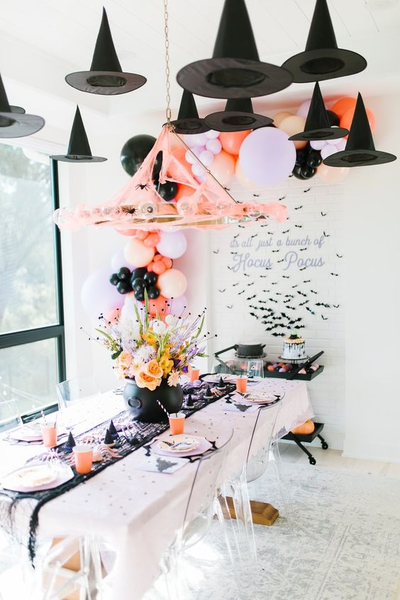 a gorgeous kids' party space with black witches' hats, balloons, bold blooms in the cauldron and printed plates