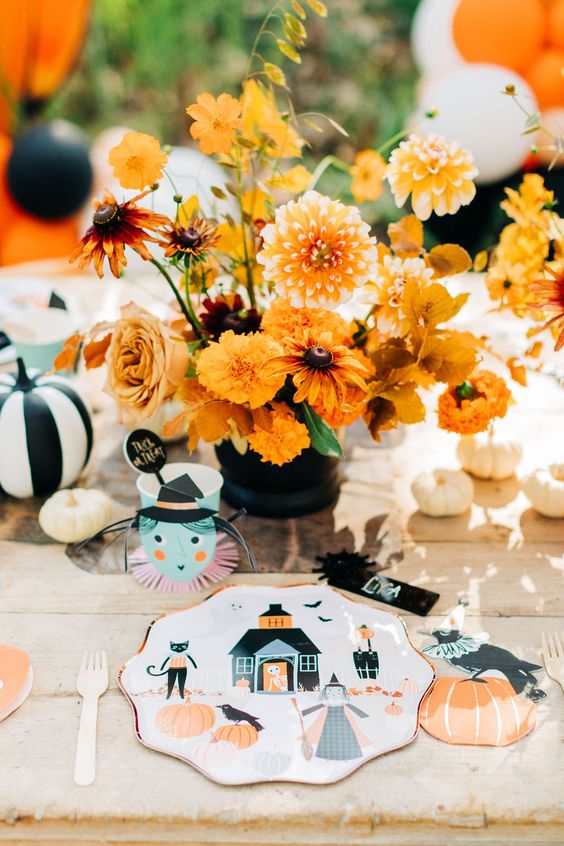 a gorgeous vintage Halloween party tablescape for kids, with bright blooms, fun printed plates and white and striped pumpkins