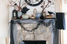a haunted Halloween mantel with blackbirds, branches, garlands, a mirror and some pumpkins