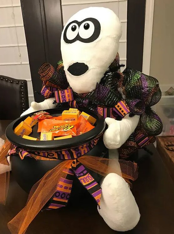 a mummy holding a witch's cauldron with sweets and candies is a great idea for styling your porch at Halloween