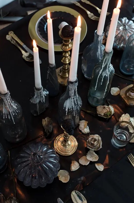 a refined Halloween tablescape with candles, dried petals, black pumpkins and touches of gold here and there