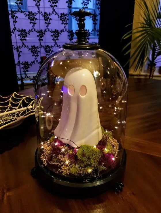 a simple Halloween cloche with moss, bold dried blooms, lights and a funky ghost figurine is a cool idea for a kids' party