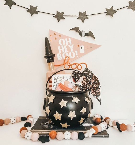 a star cauldron with various Halloween stuff, stars, bats and pompom garlands for kids' parties