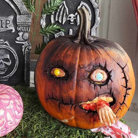 a very scary zombie pumpkin with a human hand is a catchy and bold idea to go for
