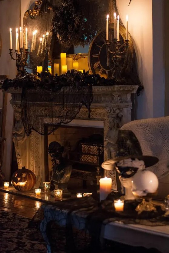 a vintage Halloween fireplace with black spiderweb and pillar candles, vintage candelabras, jack o lanterns and black faux blooms