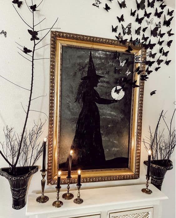 black Halloween decor with candles, black branches with black and white butterflies and a black witch artwork