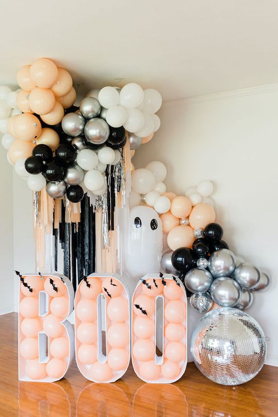 kids' Halloween party decor with peachy, black and white balloons, BOO letters and a disco ball