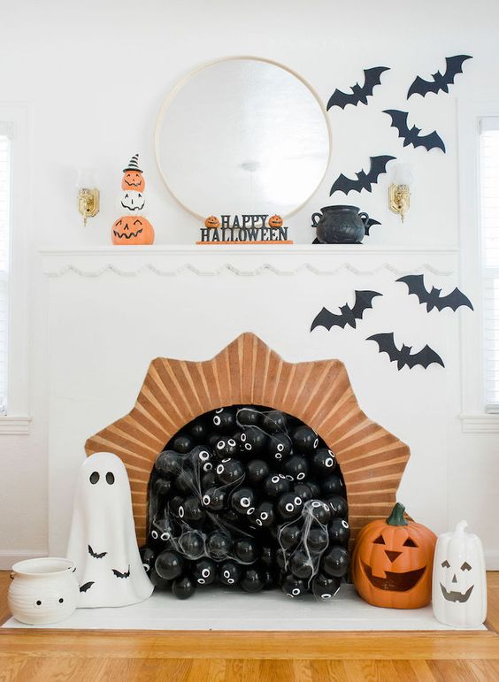 stylish and fun Halloween decor with black balloons in the fireplace, black bats, ghosts, jack-o-lanterns and pumpkins