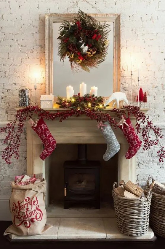 Christmas decor done with baskets, with pillar candles, evergreens, pinecones, red berries and red and grey printed Christmas stockings
