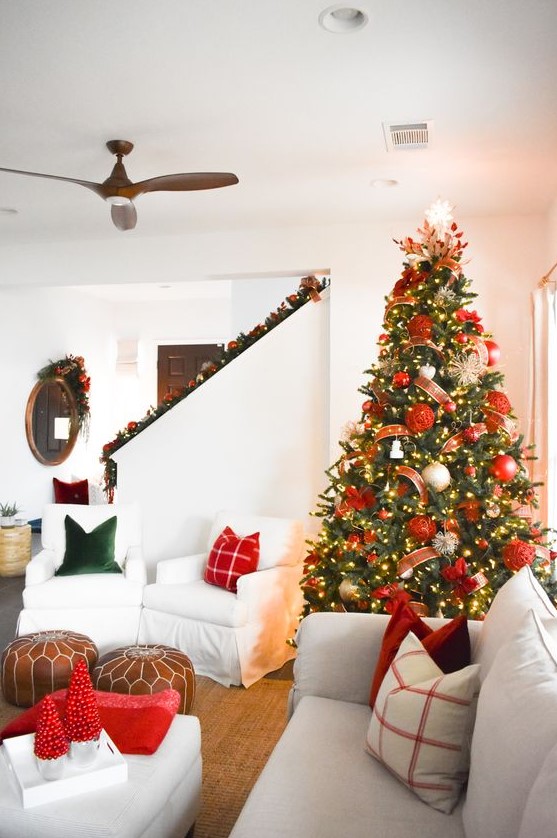 a Christmas tree with lights, red and gold ornaments, ribbons and a shiny snowflake topper