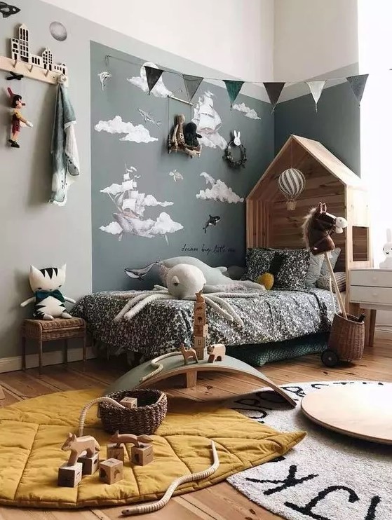 a Nordic kid's bedroom with an accent corner, a wooden house-shaped bed with printed bedding, layered rugs, buntings and racks