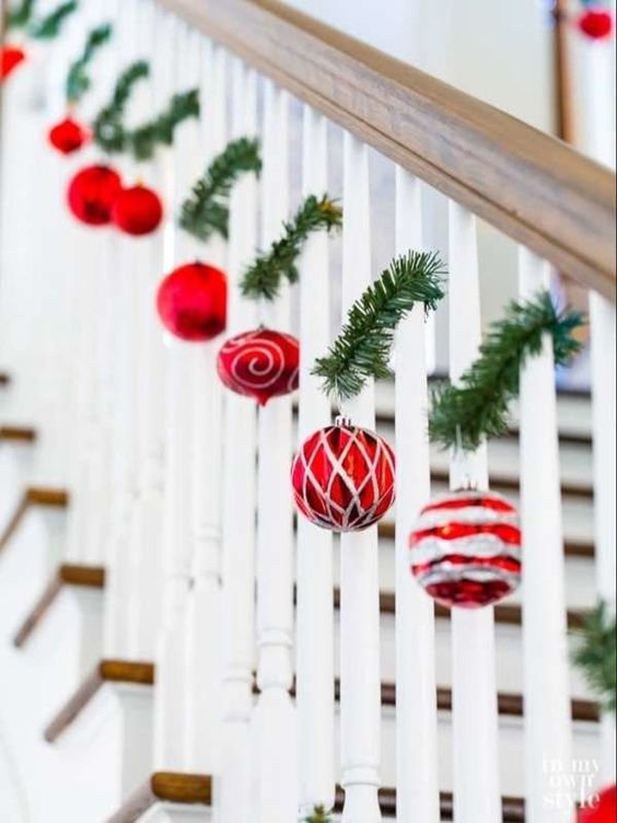 a banister decorated with evergreens and red and silver ornaments is a beautiful idea for Christmas