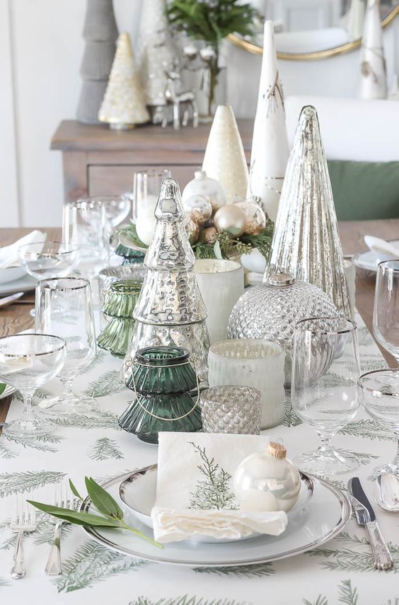 a beautiful Christmas tablescape with mercury glass trees and candleholders, metallic ornaments and evergreens