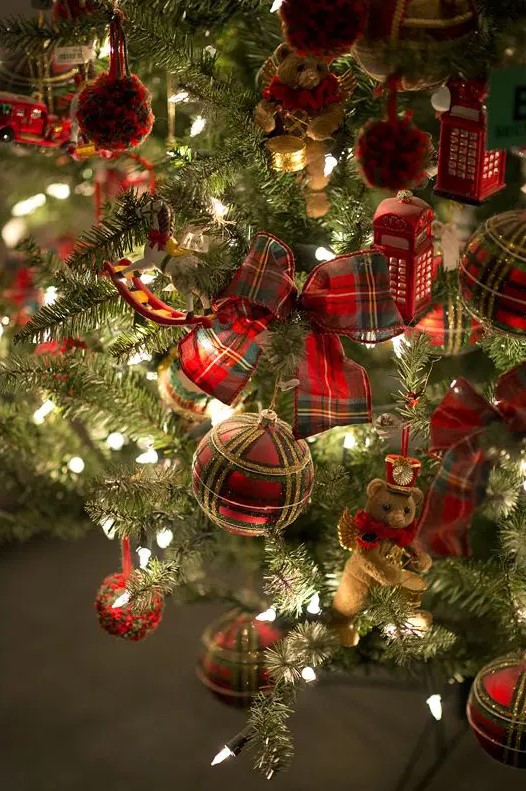 a beautiful Christmas tree decorated with plaid baubles, ribbons, pompoms, mini teddy bears and red phone boxes plus lights is very whimsy