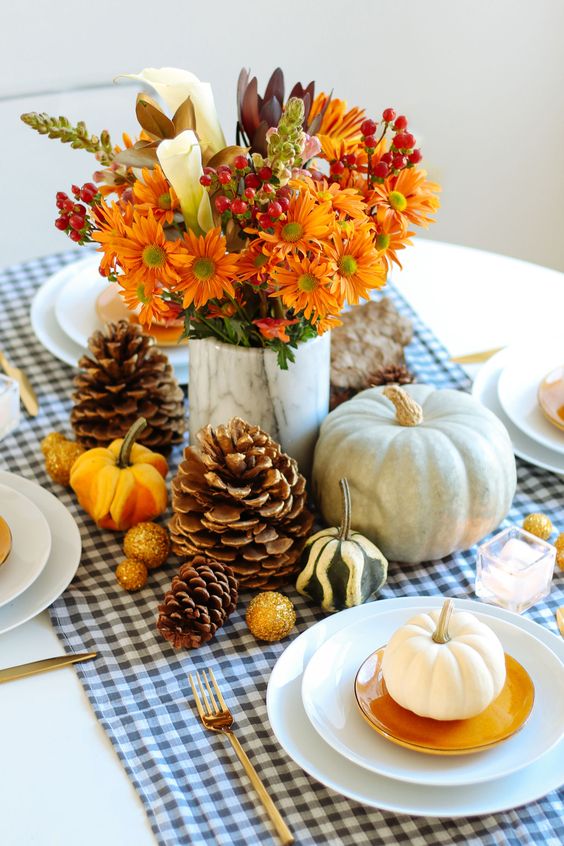 a beautiful and all-natural Thanksgiving centerpiece of mini and larger pumpkins, pinecones, bold blooms and berries is awesome