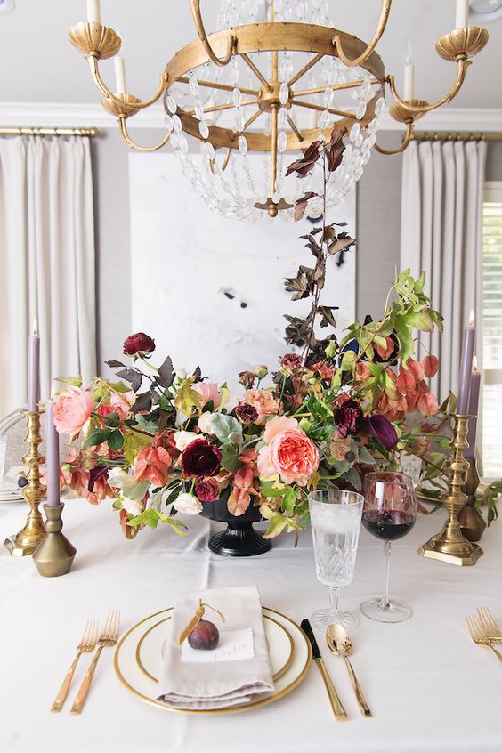 a beautiful and chic floral Thanksgiving centerpiece of purple, pink and burgundy blooms, greenery and dark foliage is a lovely idea