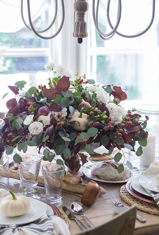 a beautiful and natural Thanksgiving centerpiece of usual and dark foliage, white pumpkins, berries and white blooms