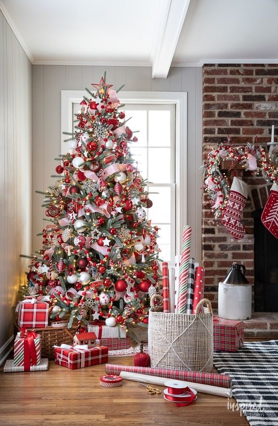 a beautiful red and white Christmas tree decorated with regular baubles and stars, ribbons, candy canes and beads is wow