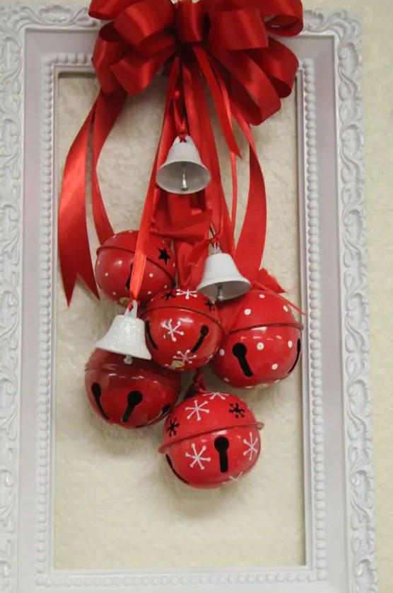 a bold Christmas decoration of a white frame, red Christmas bells and mini white ones, a red bow