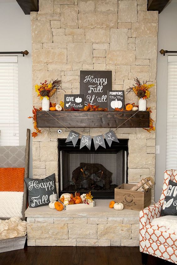 a bold Thanksgiving mantel with lots of dried leaves, wheat, pumpkins of various materials, garlands and several signs