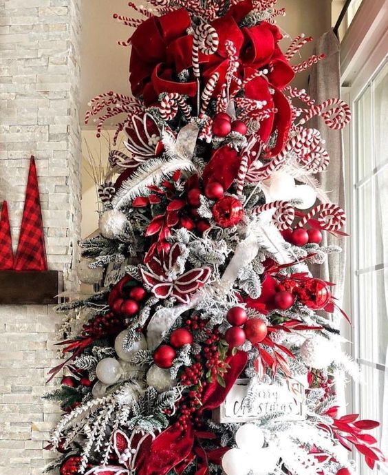 a bold flocked Christmas tree with red and white ornaments, feathers, red ribbons, candy canes and a sign