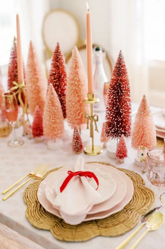 a bold holiday table with red and pink bottle brush trees, pink candles, woven placemats and pink porcelain