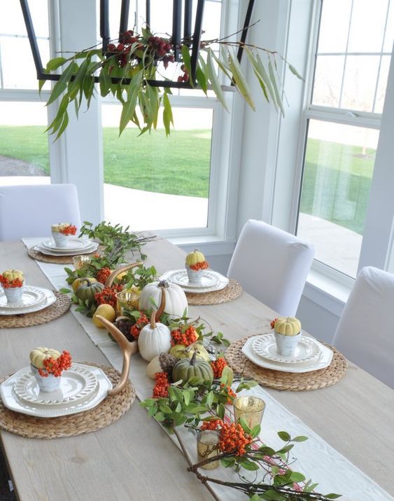 a bold natural Thanksgiving centerpiece and table runner of green, yellow and white pumpkins, berries and greenery plus candles