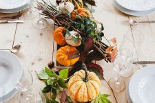 a bold rustic Thanksgiving centerpiece of pumpkins, fruits, greenery, branches and candles is a very cool and bold idea