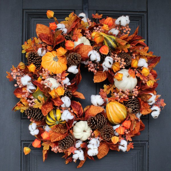 a bright Thanksgiving wreath with pinecones, gourds, pumpkins, leaves and dried blooms is a very eye-catchy solution